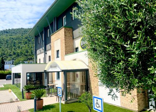 un bâtiment avec un panneau devant lui dans l'établissement B&B HOTEL Aubagne Gémenos, à Gémenos