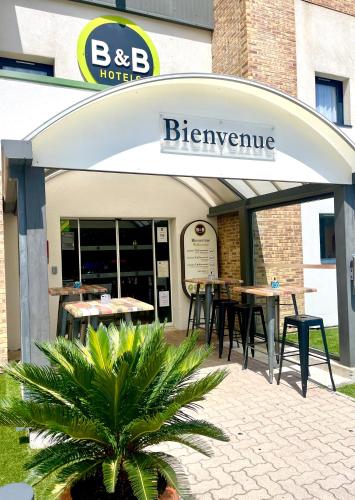 un restaurant avec des tables et des chaises devant un bâtiment dans l'établissement B&B HOTEL Aubagne Gémenos, à Gémenos
