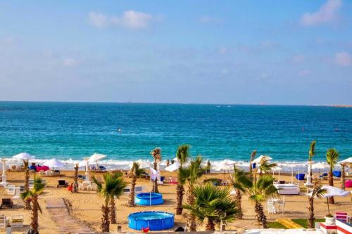 una playa con palmeras y el océano en Paradise Inn Beach Resort, en Alejandría