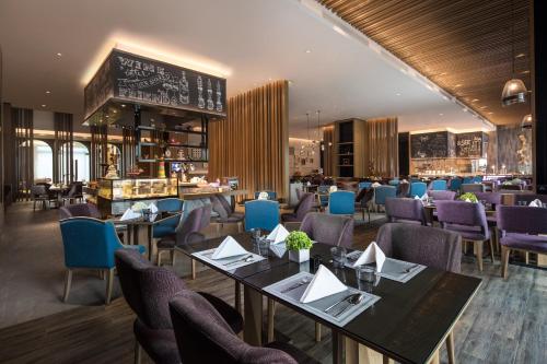 un restaurante con mesas y sillas y un bar en Crowne Plaza QingdaoOrientalMovieMetropolis, an IHG Hotel, en Huangdao