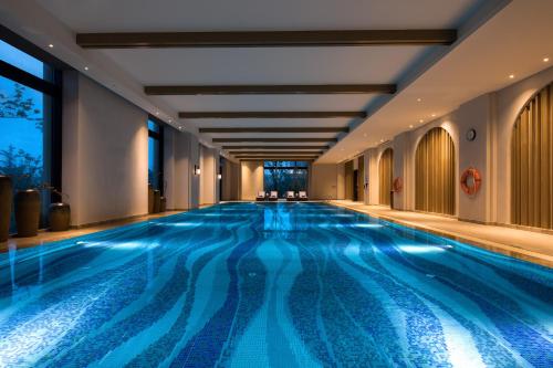 una piscina en un hotel con iluminación azul en Crowne Plaza QingdaoOrientalMovieMetropolis, an IHG Hotel, en Huangdao