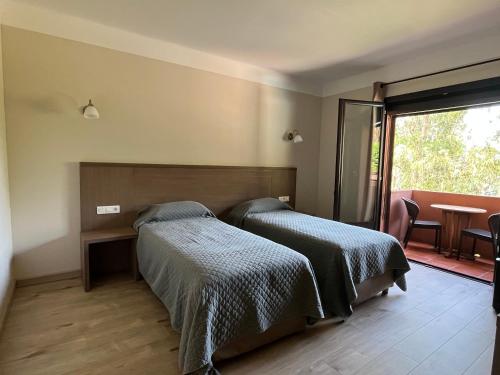 a bedroom with two beds and a balcony with a table at Hotel Corsica - Porto Corse in Porto Ota