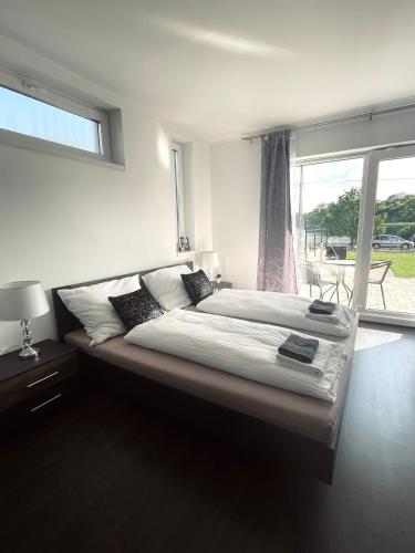 duże łóżko w sypialni z oknem w obiekcie Lux apartments w mieście Orosháza