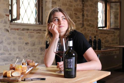 a woman sitting at a table with a bottle of wine at B&B - Relais de charme la Caminella in San Pietro in Cariano