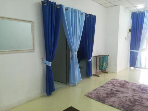 Cette chambre dispose de rideaux bleus et d'un tapis. dans l'établissement Homestay siti, à Padang Serai