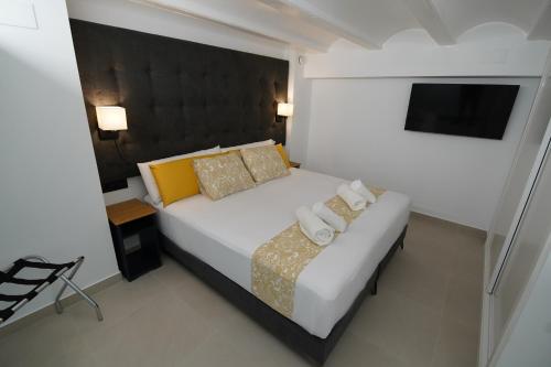 a bedroom with a white bed and a television at BET Apartments - Suites Puerto Valencia in Valencia