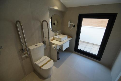 a bathroom with a toilet and a sink and a window at BET Apartments - Suites Puerto Valencia in Valencia