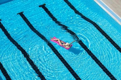a woman laying on a raft in a swimming pool at Grand Hotel & Riviera in Lido di Camaiore