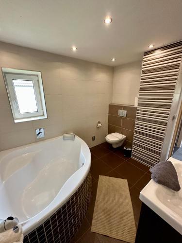 a bathroom with a large tub and a toilet at U nás na chalupě in Borovany