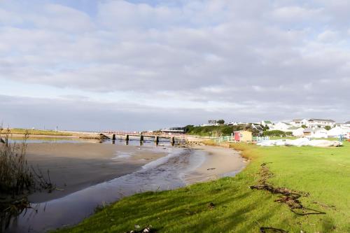 a beach with a pier and houses in the background at Shalom Self Catering in Kleinmond