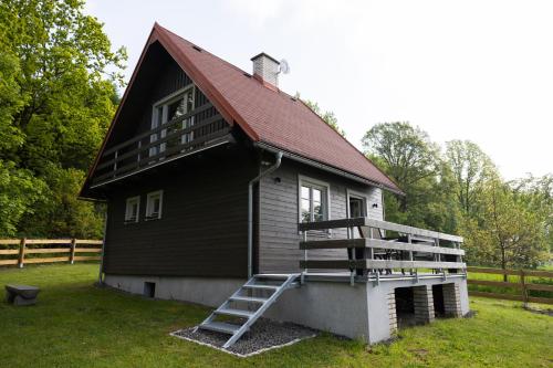 a black house with a red roof and a staircase at Chata Šedivka in Dvůr Králové nad Labem