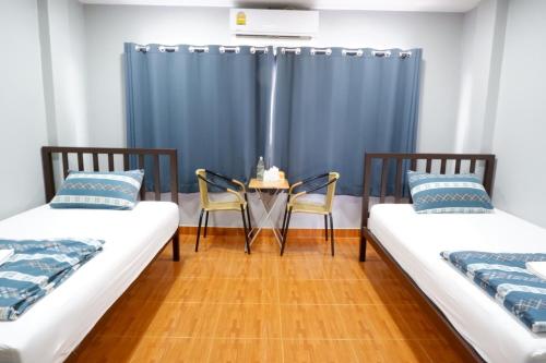 a room with two beds and a table and chairs at Chill @ Phetchaburi in Phetchaburi