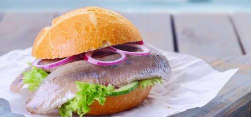 a fish sandwich with lettuce and onions on a bun at Ferienwohnungen Seestern Marina Port of Wendtorf in Wendtorf