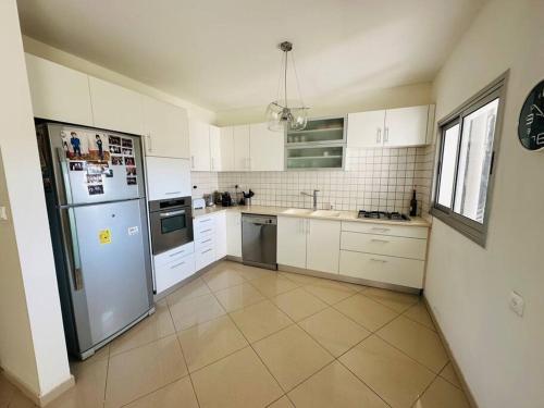  La cuisine est équipée de placards blancs et d'un réfrigérateur. dans l'établissement Vacance, à Ashkelon
