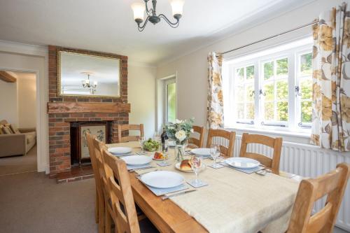 a dining room with a table and a fireplace at Spacious family cottage with private garden and forest walks in Burley
