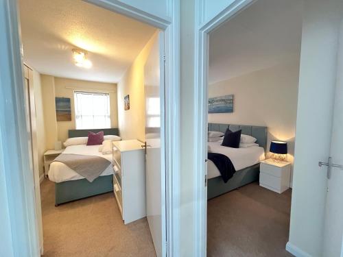 a bedroom with two beds and a mirror at Penny Cottage By The Beach in Portsmouth