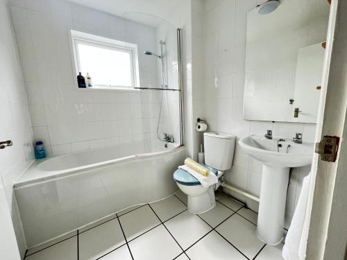 a bathroom with a tub and a toilet and a sink at Penny Cottage By The Beach in Portsmouth