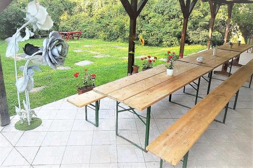 a row of wooden tables in a garden at Muskátli Vendégház in Parádfürdő-Peres