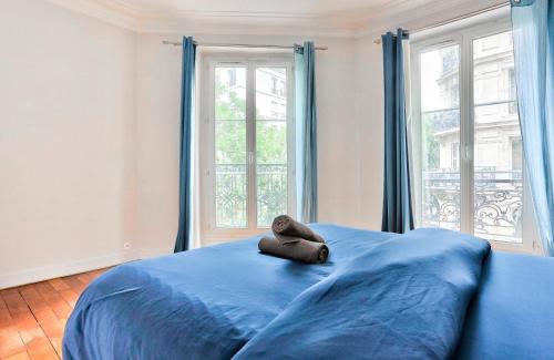 een blauw bed met een paar schoenen erop. bij Appartement Quartier Parc Monceau in Parijs