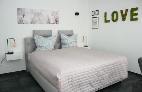 a bedroom with a white bed with a love sign on the wall at Ferienwohnung Die Traumhafte in Kleve