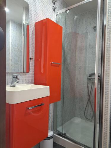 um armário laranja na casa de banho com um lavatório e um chuveiro em Estudio en primera línea de mar em Empuriabrava