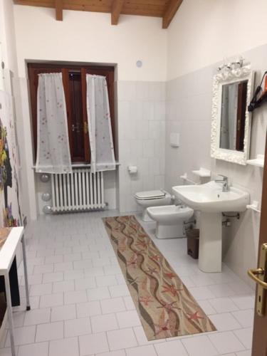 a white bathroom with a sink and a toilet at Foresto Case Vacanza in Volta Mantovana