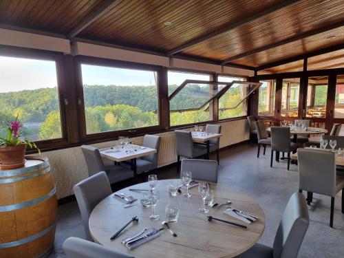 un restaurant avec des tables, des chaises et des fenêtres dans l'établissement Hôtel du Lac, à Lacapelle-Viescamp