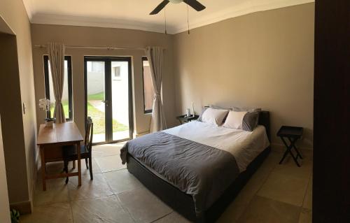 a bedroom with a bed and a desk and a window at Apartment @ Silver Lakes in Pretoria