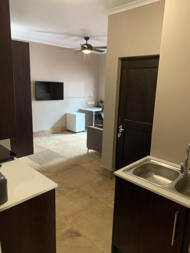 a kitchen with a sink and a living room at Apartment @ Silver Lakes in Pretoria