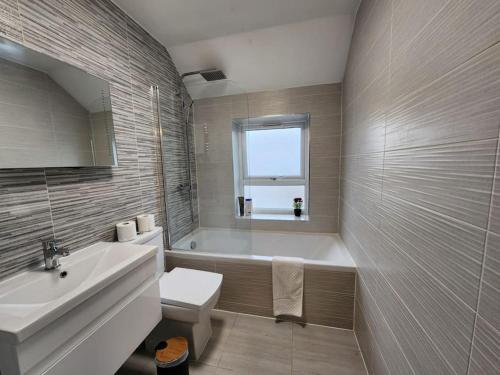 a bathroom with a tub and a toilet and a sink at Horizon House, Modern 2-Bedroom Flat 2, Parking, Netflix, Oxford in Oxford