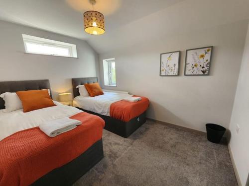 een slaapkamer met 2 bedden met oranje lakens bij Horizon House, Modern 2-Bedroom Flat 2, Parking, Netflix, Oxford in Oxford