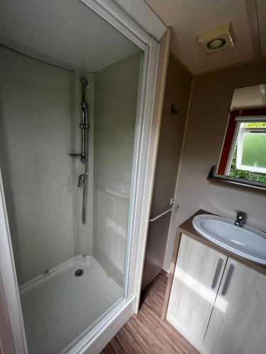 une salle de bain avec douche et lavabo dans l'établissement Mobil Home Cosi Climatisé pour 6 - Camping Tohapi, à Vogelgrun