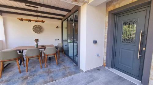 a dining room with a wooden table and chairs and a blue door at Danielli Luxury Villas in Skala Rachoniou