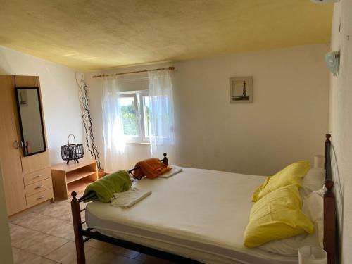 een slaapkamer met een bed met gele en groene kussens bij Apartmani Fijan in Pag