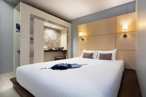 a bedroom with a large white bed with an umbrella on it at Montree Phuket Hotel in Phuket Town