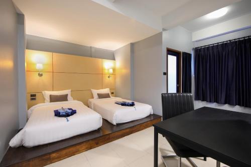 two beds in a room with a table and a desk at Montree Phuket Hotel, SHA Extra Plus in Phuket Town