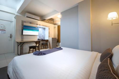 a hotel room with a large white bed and a desk at Montree Phuket Hotel in Phuket Town