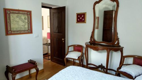 um quarto com um espelho, uma cama e uma cadeira em Alloggio dell'Antica Torre em Garessio