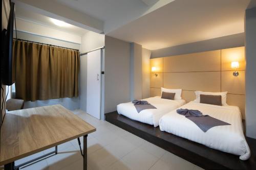 a bedroom with two beds and a table at Montree Phuket Hotel in Phuket Town