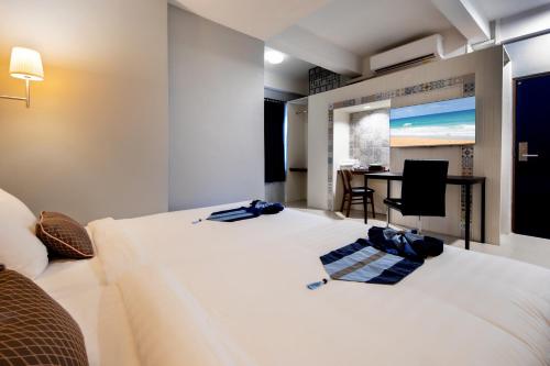 a bedroom with a large white bed and a table at Montree Phuket Hotel in Phuket Town