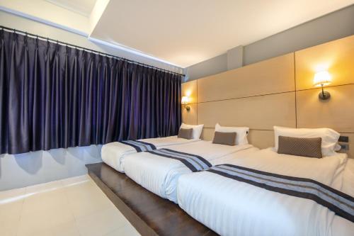 two beds in a hotel room with purple curtains at Montree Phuket Hotel in Phuket Town