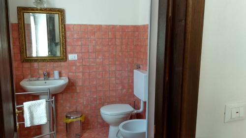 uma casa de banho com um WC, um lavatório e um espelho. em Alloggio dell'Antica Torre em Garessio