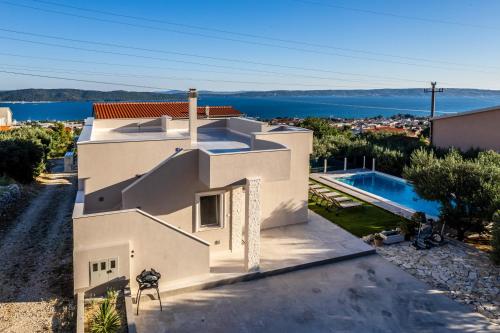 uma vista aérea de uma casa branca com uma piscina em Villa Dalmatina Hill House - private pool, sea and hill view, rooftop terrace, free parking em Kaštela