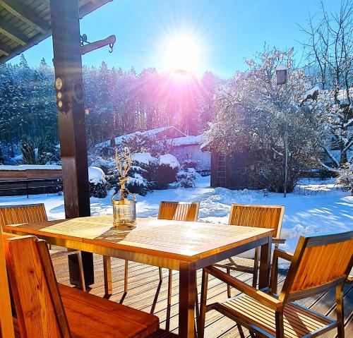 a wooden table and chairs on a porch with snow at Chalet Anna in Unterwössen