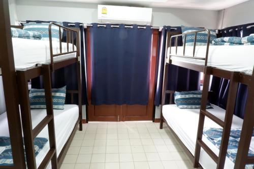 a room with three bunk beds with blue curtains at Chill @ Phetchaburi in Phetchaburi