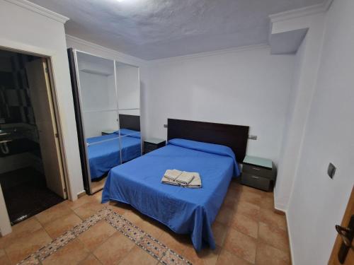 a bedroom with a blue bed with a blue blanket at Habitaciones y Estudios Miramar in Bolonia