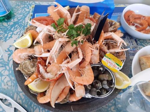 une assiette de crevettes et autres fruits de mer sur une table dans l'établissement Cabourg Charmant studio centre ville RUE DE LA MER, à Cabourg