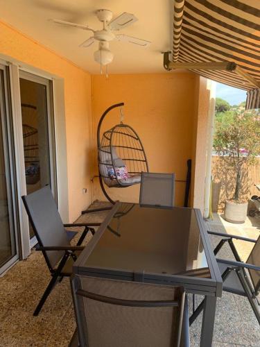 une table et des chaises dans une pièce avec une cage à oiseaux dans l'établissement Marinella, vue mer panoramique, superbe T2 plage à 150 m, à Ajaccio