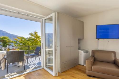 sala de estar con una puerta corredera de cristal que da a un balcón en Lake Paradise, en Brissago