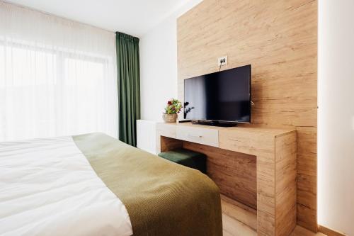a hotel room with a bed and a flat screen tv at Blumenhof Bucovina in Voronet